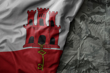 waving flag of gibraltar on the old khaki texture background. military concept.