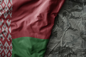 waving flag of belarus on the old khaki texture background. military concept.