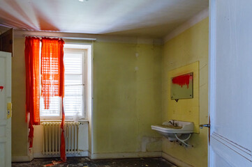 Chambre délabrée avec lavabo et rideaux déchirés