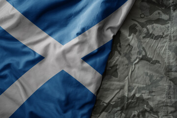 waving flag of scotland on the old khaki texture background. military concept.