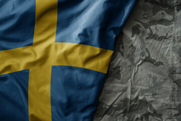 waving flag of sweden on the old khaki texture background. military concept.