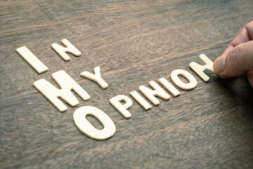 Hand arranges the wooden letters on the desk as IMO acronym or In My Opinion, used as a brief...