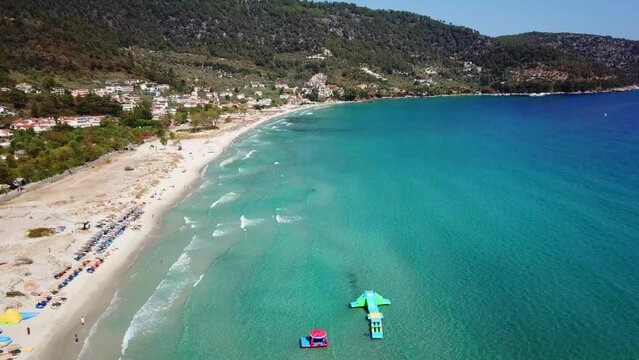 Aerial drone view from above the Aegean sea of the shore of the Golden Beach area in Thassos Island , Greece , showing the resorts and hotels , tourist accommodation , the pure white sand shore
