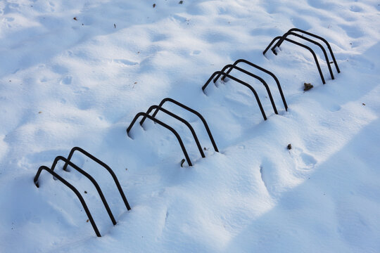 a winter landscape with metal bicycle holders covered in snow 