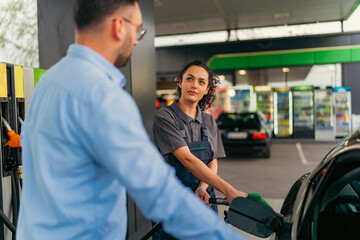 Fototapeta na wymiar A worker at a gas station fills customers gas tank