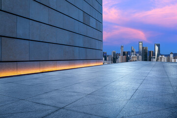 Pedestrian walkway and brick wall with city skyline at sunset