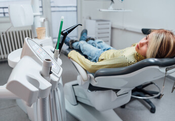Medical dental chair vacuum instruments photo. Little girl sitting in stomatology clinic chair after teeth dental procedures. Healthcare, kid's health and medicare industry concept image.