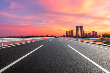 Straight asphalt road and Suzhou skyline with modern buildings at sunset, Jiangsu Province, China.