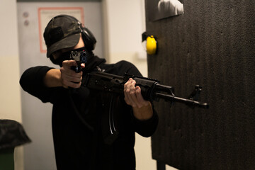 The shooter is holding an Ak 47 and a SP 01 CZ Shadow pistol - obrazy, fototapety, plakaty