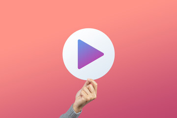 Hand holding white media player button icon on red background. Video play presentation