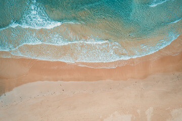 Aerial view to tropical sandy beach and blue ocean. Top view of ocean waves reaching shore on sunny day. Palawan, Philippines.