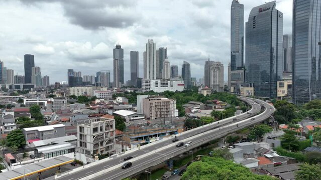cloudy day flight over jakarta city downtown traffic street road overpass aerial panorama 4k indonesia