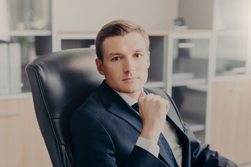 Confident male executive with focused gaze seated at office desk
