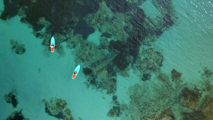 Drone top aerial view of friends with paddles and kayak on turquoise water of Mediterranean sea of Sardinia, Italy