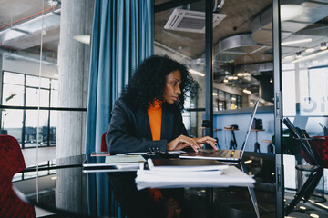 Engrossed Black data analyst in her 30s, meticulously evaluating complex datasets on her laptop 