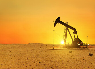 Pumpjack rig pumps oil in the desert at sunset. Dead land and sand, concept. Global warming,...