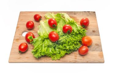 Bright red cherry tomatoes and green lettuce on a wooden board. Vegan food. Salad preparation.