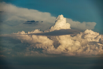 Cumulus congestus clouds climbing dramatically into a late summer afternoon sky before a background...