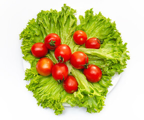 Green fresh lettuce leaves with juicy cherry tomatoes in a white bowl. Isolated on white background.