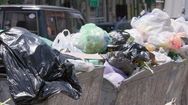 overfilled public trash bins at summer day in large city, close-up slow motion.