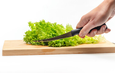 Cutting fresh green salad on a wooden kitchen board. Side view. Female hand with a knife.