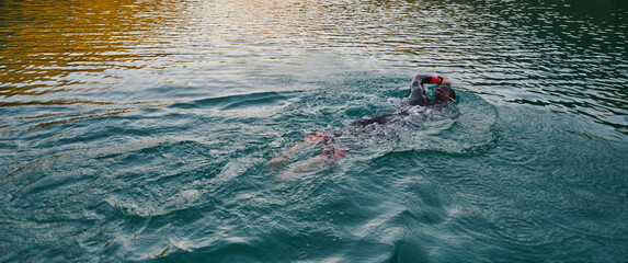 A professional triathlete trains with unwavering dedication for an upcoming competition at a lake,...