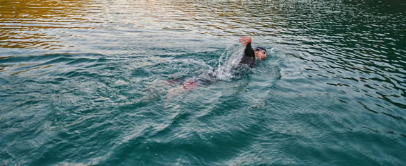 A professional triathlete trains with unwavering dedication for an upcoming competition at a lake,...