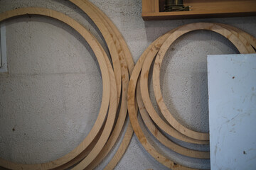 Circular wooden frames lean against a textured wall, their smooth curves a stark contrast to the...