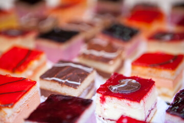 The image is a vibrant and appetizing close-up of assorted petit fours, each meticulously crafted...