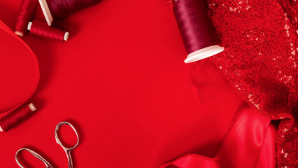 Fashion designer's workplace. sewing business. Red satin or silk fabric with sewing accessories, scissors, threads