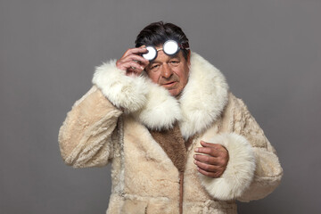 A mature man in a warm fur coat with a white fox collar and sunglasses.