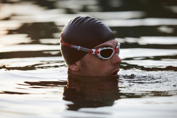 A triathlete finds serene rejuvenation in a lake, basking in the tranquility of the water after an...