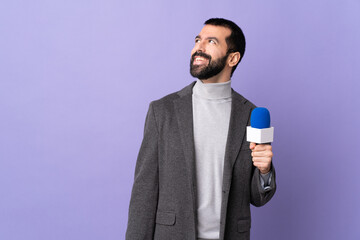 Adult reporter man with beard holding a microphone over isolated purple background thinking an idea...