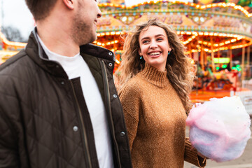 Couple having fun and eating cotton candy at amusement park in London