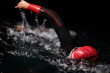 A determined professional triathlete undergoes rigorous night time training in cold waters,...