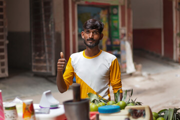 Male vendor showing thumbs up at his roadside juice shop