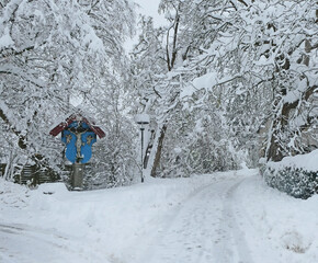 Winter in Bavaria, small chapel at a crossing point with two rural road near a wood, under heavy snowfall and a deep cover of white snow