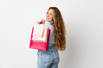 Fototapeta premium Young blonde woman isolated on white background holding shopping bags and smiling