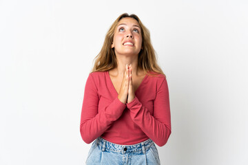 Young blonde woman isolated on blue background keeps palm together. Person asks for something