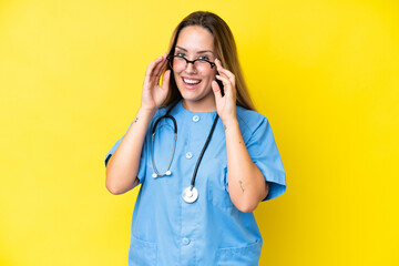 Young surgeon nurse woman isolated on yellow background with glasses and surprised