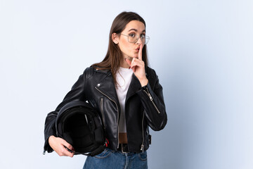 Young woman holding a motorcycle helmet over isolated blue background doing silence gesture