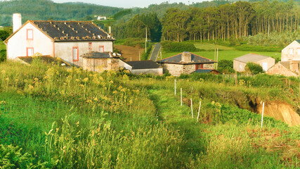A small village with a horreo surrounded by forests, fields and mountains.