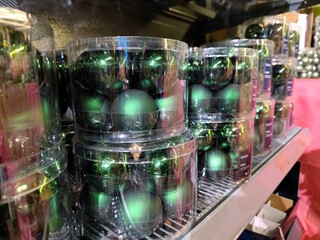Green colored Christmas baubles in baskets on store shelves ready to be sold to visitors during a Christmas show during Christmas season