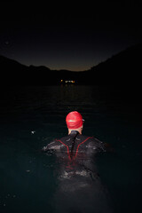 A determined professional triathlete undergoes rigorous night time training in cold waters,...