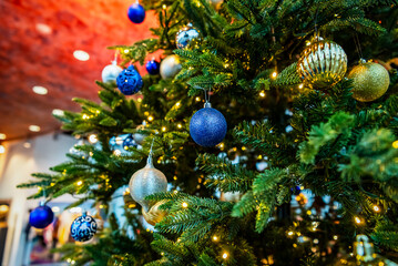 Obraz na płótnie Canvas Christmas tree decorated with blue and gold balls and garlands