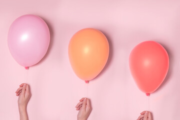Pastel pink and colorfool balloons with females hands. Party concept.