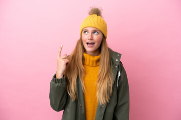 Young blonde woman wearing winter jacket isolated on pink background thinking an idea pointing the finger up