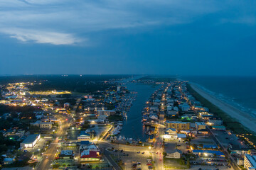 an aerial shot along the coastline of the Atlantic ocean with blue water, a sandy beach, hotels and condominiums and cars on the street at night with lights in Carolina Beach North Carolina USA