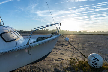 Marée basse, bateau et couché de soleil sur le bassin d'Arcachon. - obrazy, fototapety, plakaty