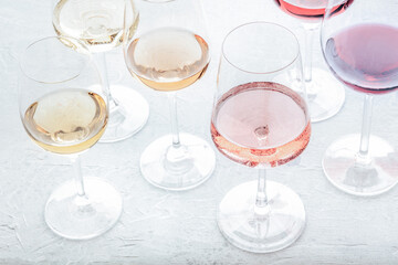 Wine glasses at a tasting. Rose, red, and white wine, drinks on a table at a winery, toned image. An assortment of wines of different colours and hues - obrazy, fototapety, plakaty
